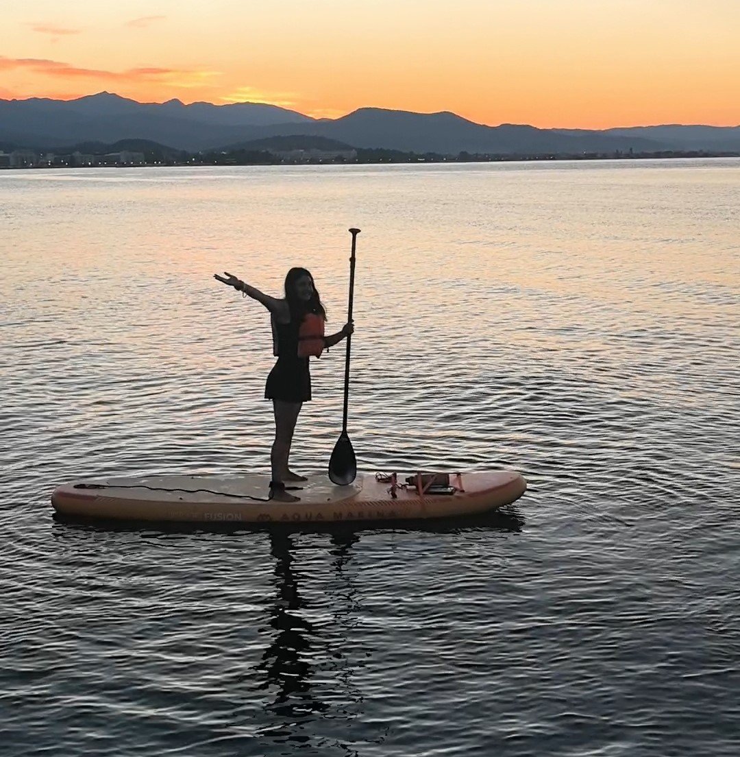 How to Stand Up Paddle Board: Complete Beginner's Guide (2026) Paddler standing tall and relaxed on a paddle board at sunset, eyes on the horizon