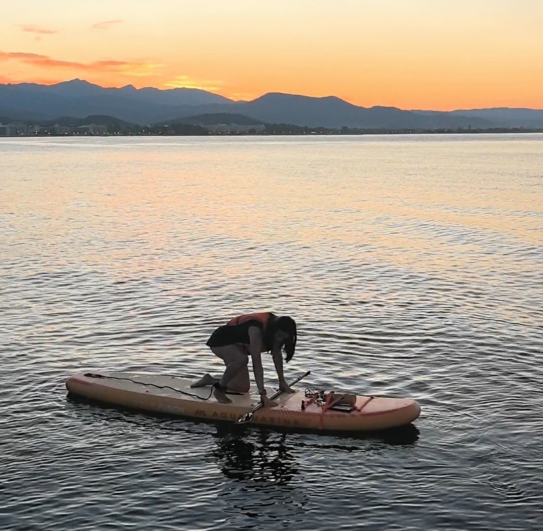 How to Stand Up Paddle Board: Complete Beginner's Guide (2026) Paddler with hands braced on the board, settling into the balance point