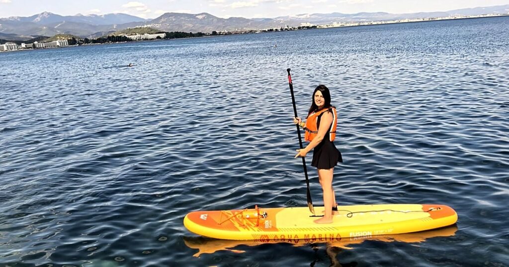 Deniz standing on an inflatable paddleboard in calm, clear water